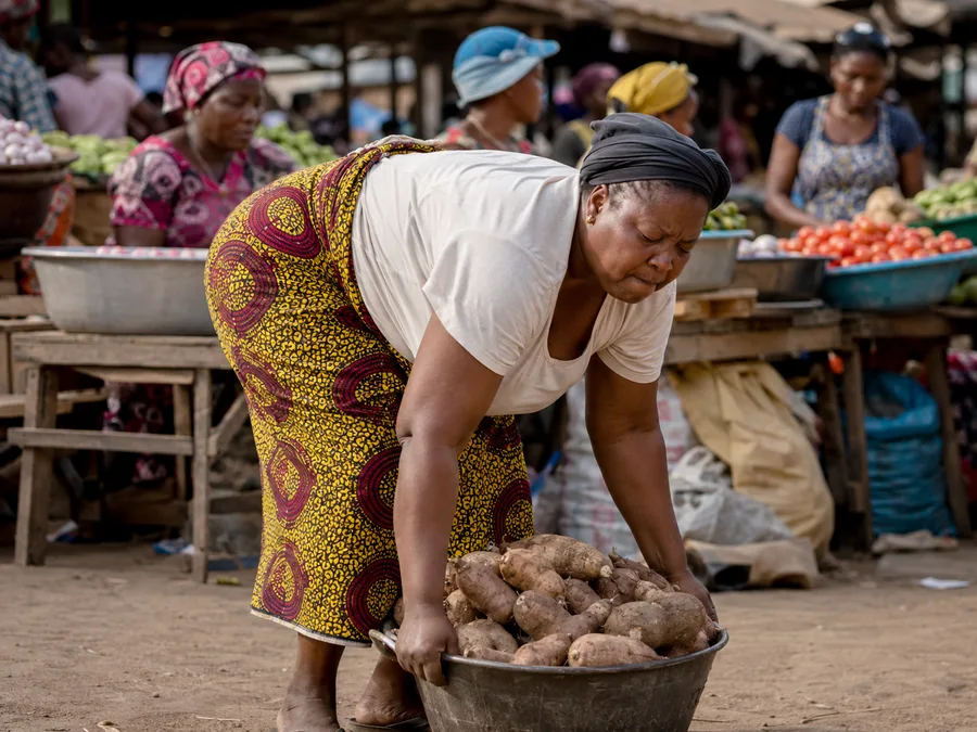 Nigerian market trader lifting a heavy basin, showing the strain everyday work puts on the joints